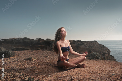 young woman practices yoga on a beach
