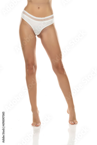 woman's legs are elegantly posed, showcasing white panties from the front on white background. Femininity, sensuality, and body positivity, 