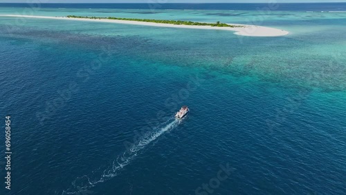 A speedboat journey unfolds as it races toward a stunning white sandbar in the Maldives, promising a day of sun, sea, and splendor aerial views photo