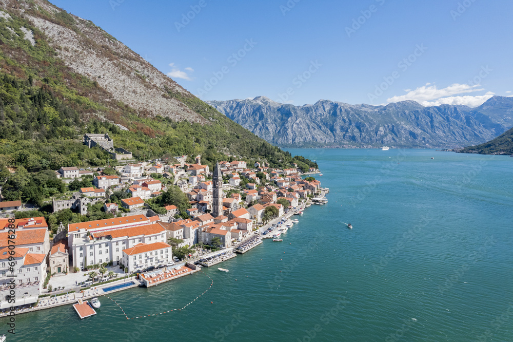 Yacht sails along the coast of Perast with ancient houses and the bell tower of the Church of St. Nicholas. Montenegro. Drone