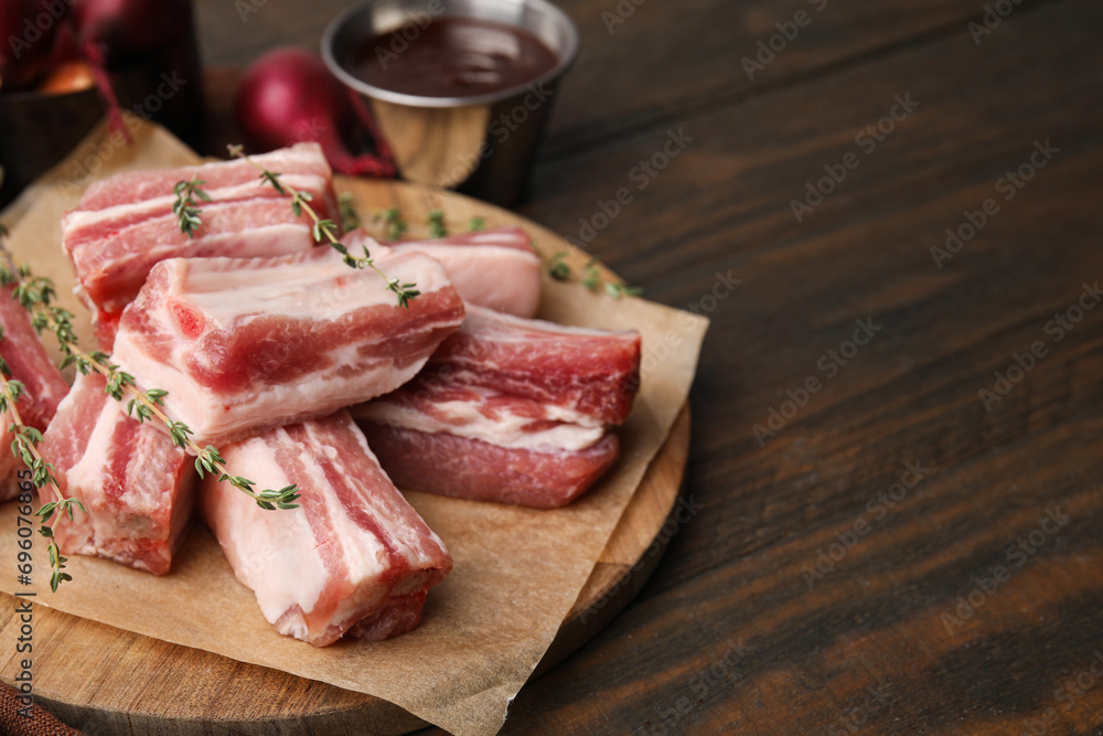 Cut raw pork ribs with thyme on wooden table. Space for text