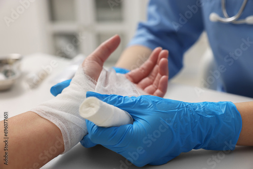 Doctor bandaging patient's burned hand in hospital, closeup photo