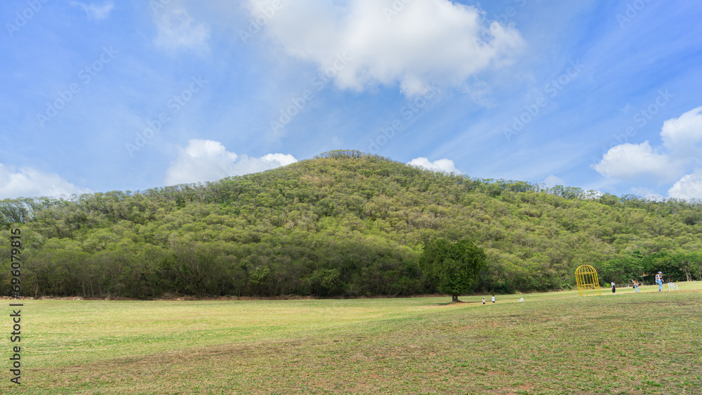 The image of the mountains is fertile. with trees growing lushly all over Amidst the bright daytime sky In front is a wide yard. Can be used for various activities