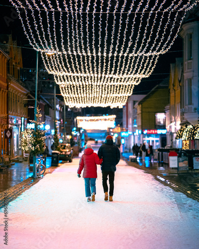 People walking down a city street in winter with christmas lights photo
