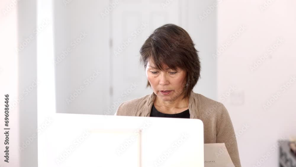 Professional stylish woman looking through folder business papers sitting at computer, monitor in foreground. Professional stylish woman looking through folder business papers sitting at computer, monitor in foreground.