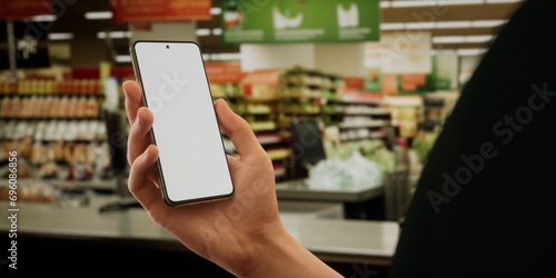 Caucasian male using his smartphone during shopping in the supermarket