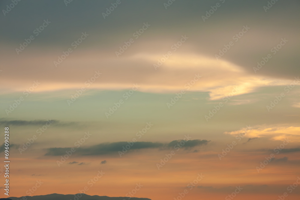 Warm foggy sunset sky with pastel romantic clouds, last rays of sun on the horizon before sunset