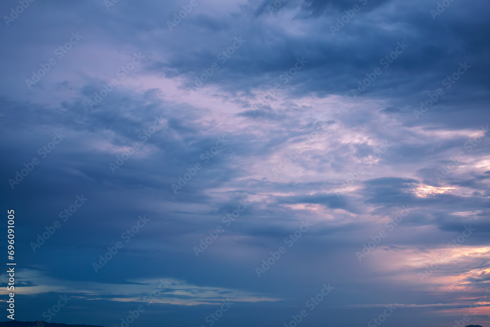 Stormy heavy violet sky with dark rainy gloomy dramatic clouds surrounded by hazy mystical atmosphere on the horizon 