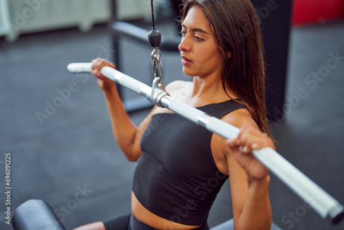 high angle view of latin woman doing wide grip lat pulldown in the gym	 photo