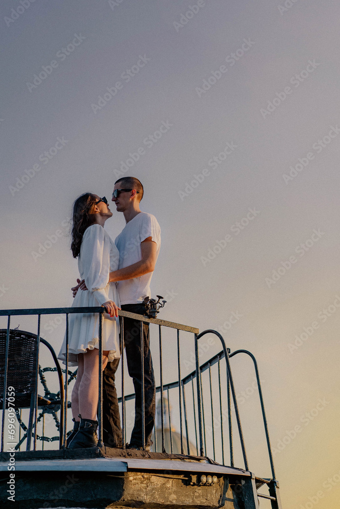 A man and woman hugging and kissing on a balcony. Rooftop in Saint-Petersburg. A man and woman hugging and kissing on a balcony. Rooftop in Saint-Petersburg.
