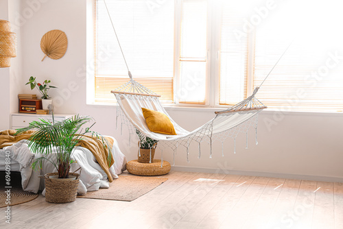 Interior of children's bedroom with cozy bed, hammock and houseplant photo