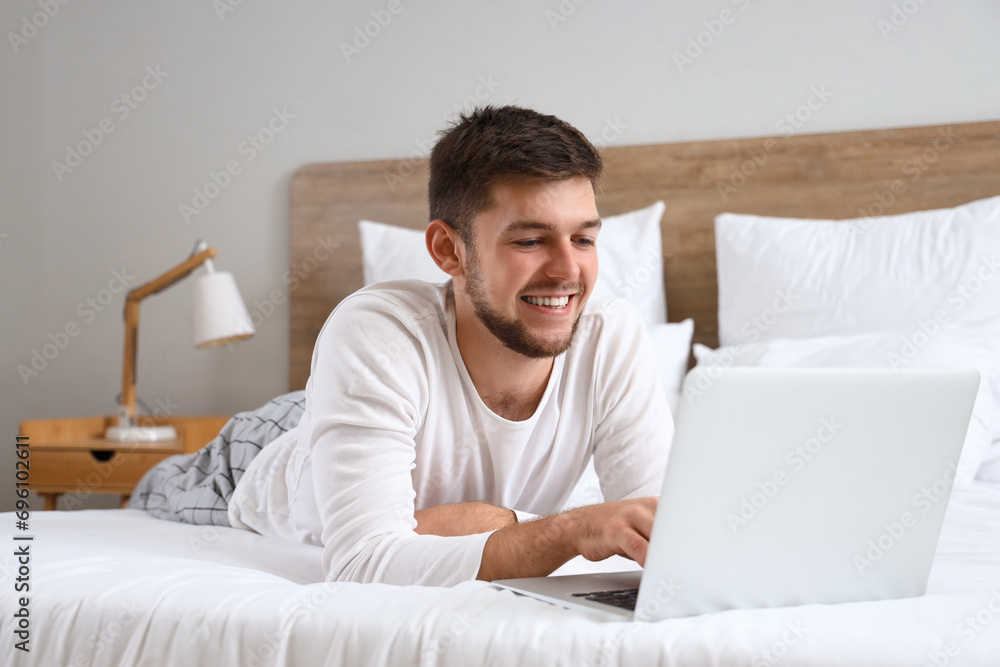 Young bearded man using laptop in bedroom Young bearded man using laptop in bedroom