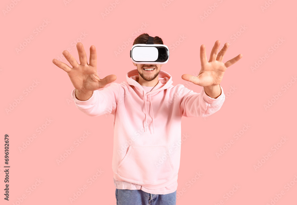 Young bearded man using VR glasses on pink background Young bearded man using VR glasses on pink background