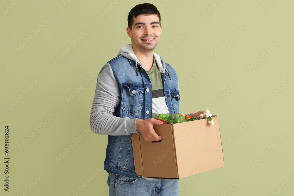 Young man with grocery box on green background Young man with grocery box on green background