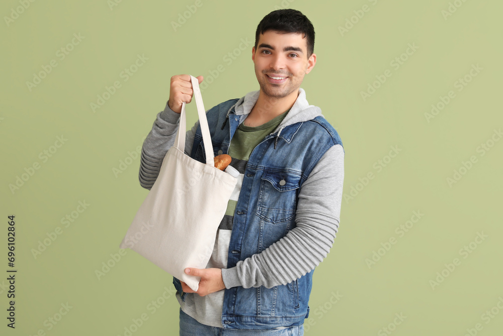 Young man with grocery bag on green background