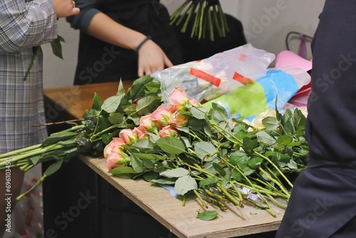 A bouquet of roses is collected and decorated in a flower shop.