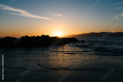 Sunset behind the rocks on the beach © Vladyslav