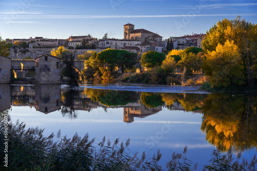 View of the city of Zamora and watermills and the San Pedro Church in the background in autmn at sunset reflected in the Duero river. Spain photo