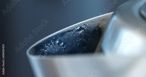 Water boils in kettle. Formation of steam and condensation on metal spout of kettle photo