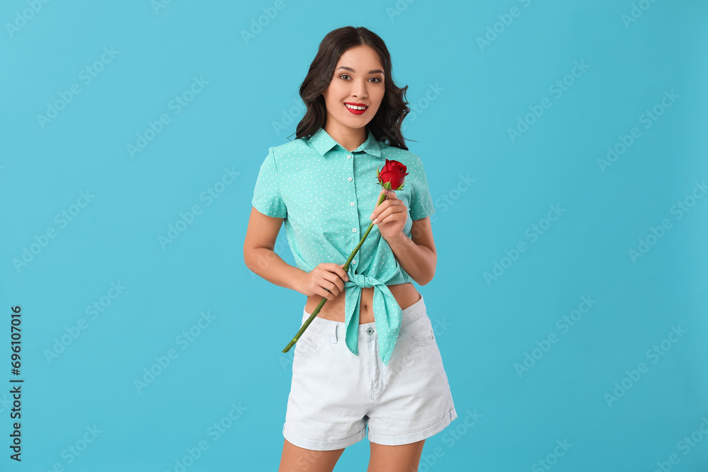 Young happy Asian woman with beautiful red rose on blue background Young happy Asian woman with beautiful red rose on blue background