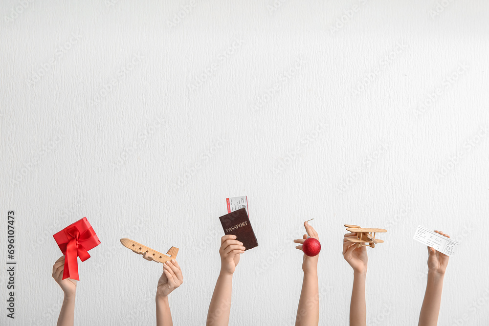 Female hands with passport, tickets, wooden planes and Christmas gift on light background - obrazy, fototapety, plakaty 