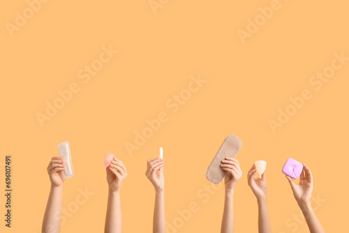 Female hands with different feminine hygiene products on color background photo