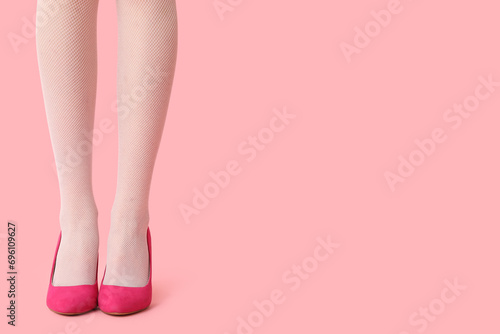 Legs of beautiful young woman in stylish high heels on pink background