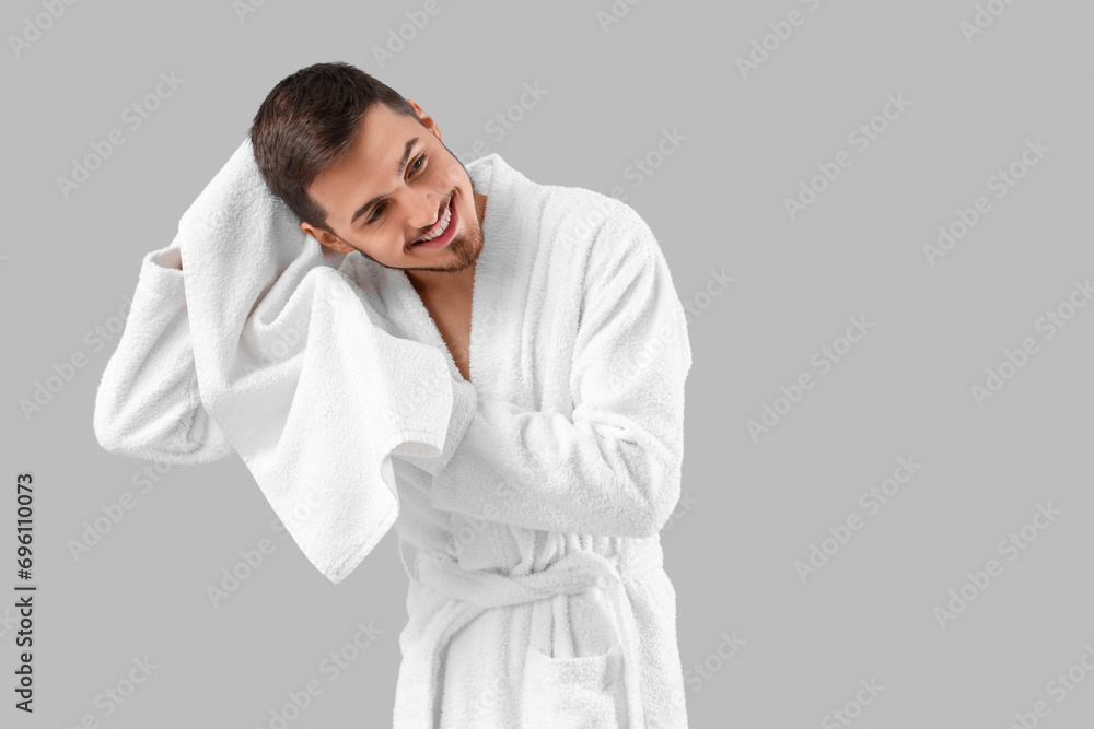 Handsome man wiping hair after washing on grey background Handsome man wiping hair after washing on grey background
