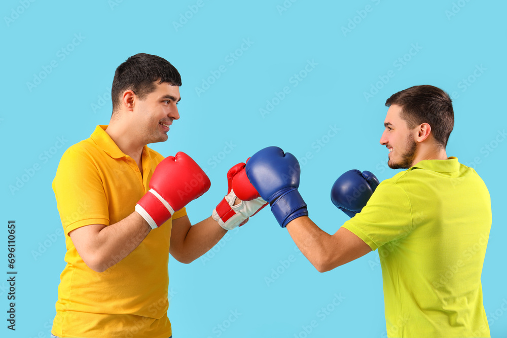 Handsome young brothers with boxing gloves on blue background Handsome young brothers with boxing gloves on blue background