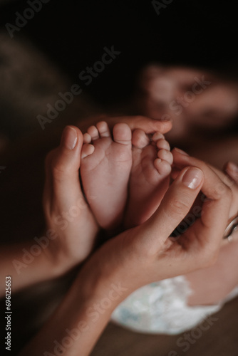 mother's hands in the shape of a heart hold the baby's legs © ilia