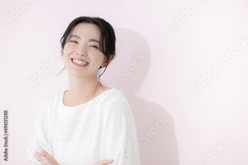 カメラ目線で白いカジュアルな服を着た笑顔の若い女性の上半身　ピンクの背景 photo