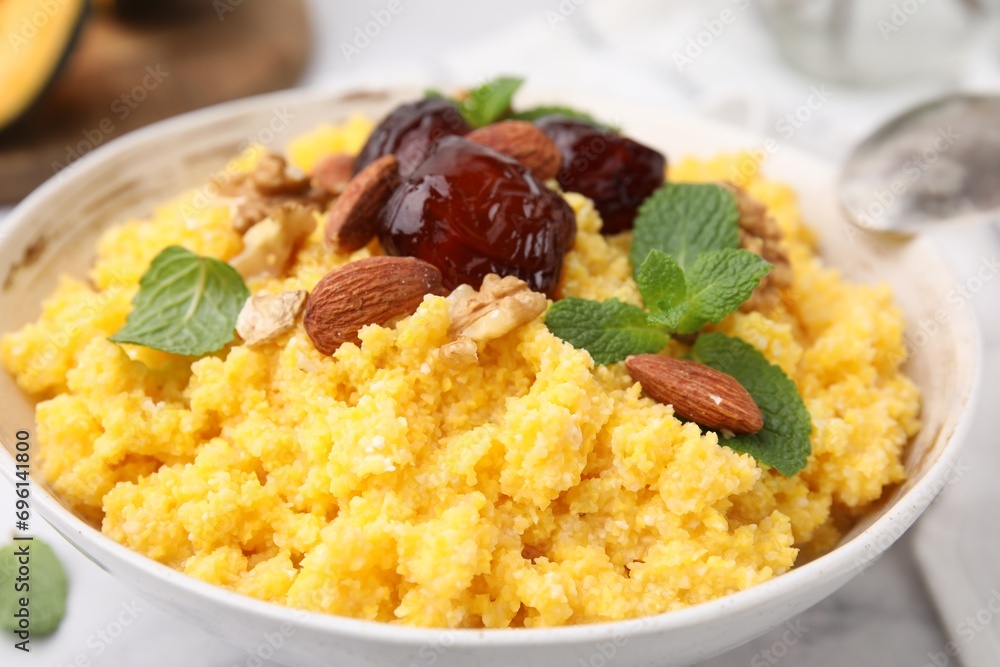 Tasty cornmeal with dates, nuts and mint in bowl on white table, closeup Tasty cornmeal with dates, nuts and mint in bowl on white table, closeup