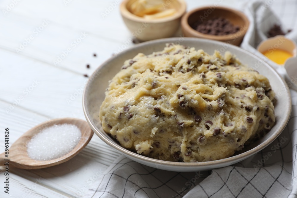 Chocolate chip cookie dough in bowl and ingredients on white wooden table Chocolate chip cookie dough in bowl and ingredients on white wooden table