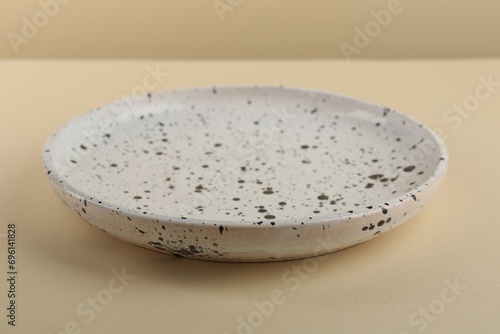 Beautiful ceramic plate on pale yellow table, closeup