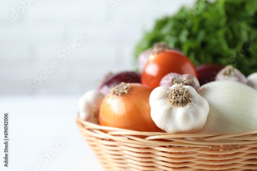 Fresh raw garlic and onions in wicker basket  closeup. Space for text