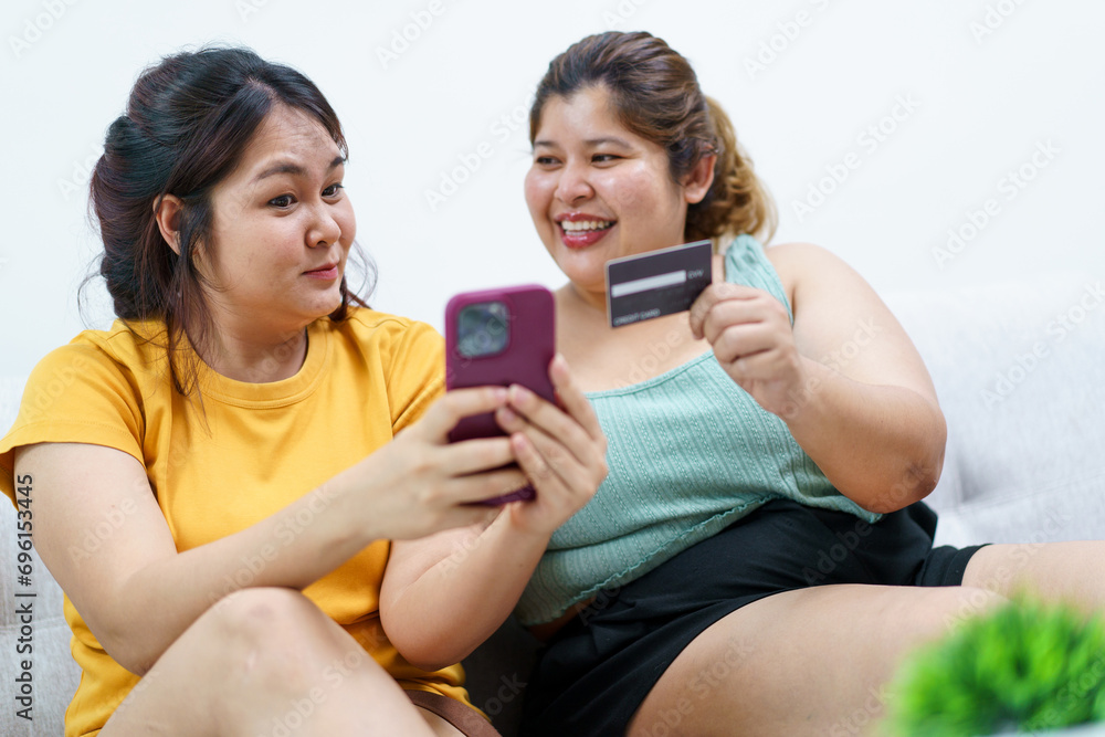 Happy - delighted two Asian oversized women talking and watching a movie on laptop or notebook computer. Happy - delighted two Asian oversized women talking and watching a movie on laptop or notebook computer.