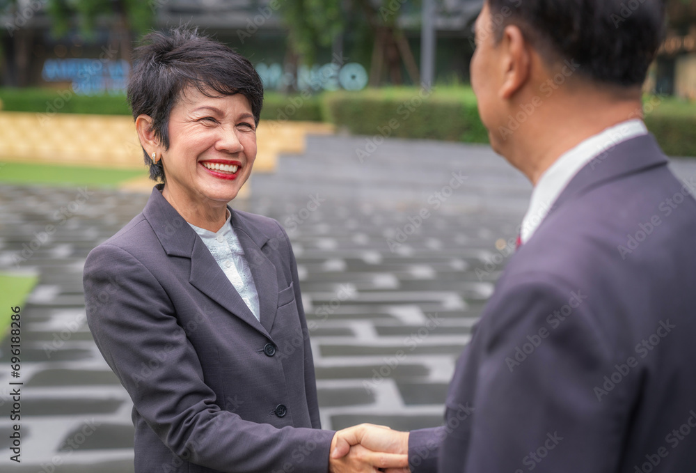 Asian old businesswoman shake hands with her customer Asian old businesswoman shake hands with her customer