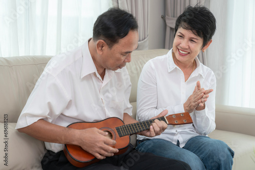 Asian okd couple sing a song and play ukulele togather in living photo