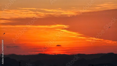 Beautiful sunset in the mountains. Sunset with beautiful orange evening sky and silhouette of mountains. Dramatic sunrise. Orange Sky. Bird in sky © Chatchaa