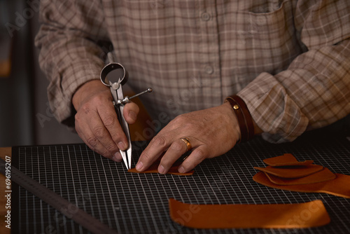 Leather marking process. focus on hands holding Wing Divider, leather Compass, necessary tools for sewing leather products