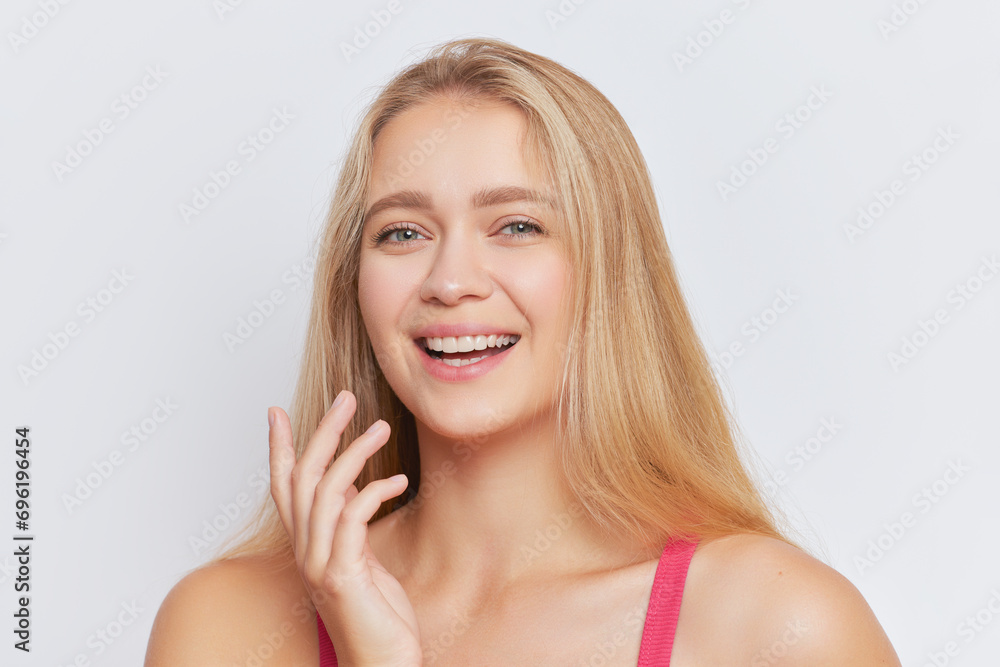 Portrait of pretty blonde girl with long hair smiling gently in front of white background, good mood concept, copy space Portrait of pretty blonde girl with long hair smiling gently in front of white background, good mood concept, copy space