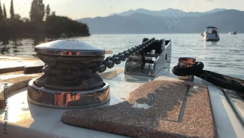 The bow of the yacht with a close-up of the device that raises the anchor chain in the glare of the setting sun