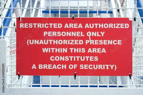 Close-Up Horizontal Frame of a Red Restricted Area Authorized Personnel Only Warning Sign on a White Metal Fence. Security Concept