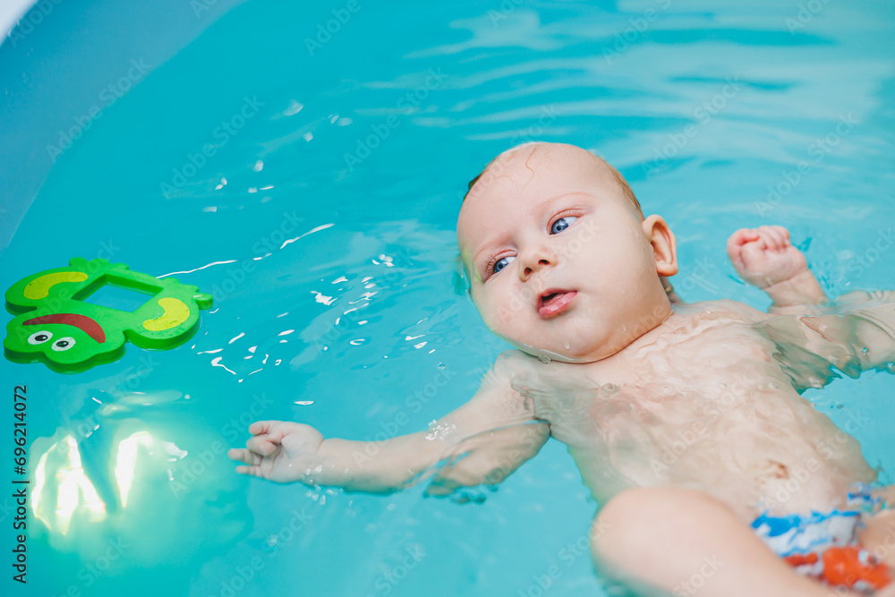 Teaching children to swim. A baby learns to swim in a pool with a trainer. Baby learning to swim. Child development. Teaching children to swim. A baby learns to swim in a pool with a trainer. Baby learning to swim. Child development.
