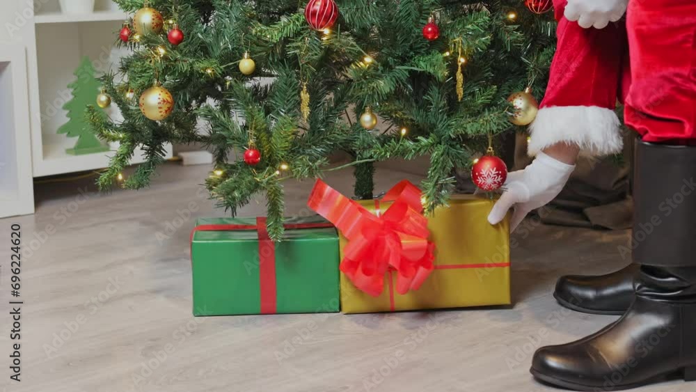 Vidéo Stock Santa Claus puts presents under the Christmas tree. A closeup of Santa Claus's boot