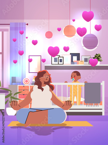 mother and newborn baby in crib spending time together in living room with pink hearts valentines day celebration concept