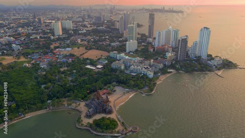 The Sanctuary of Truth wooden temple in Pattaya Thailand is a gigantic wood construction located at the cape of Naklua Pattaya City. sCity skyline of Pattay during sunset photo