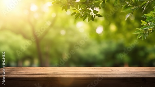 Empty wooden tabletop on blurred abstract green foliage background from garden on sunny background. Montage or design product background