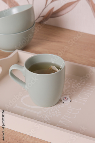 Green ceramic tea mug on the wooden tray in the kitchen