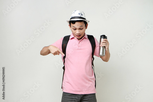 Asian man backpacker hold tumbler bottle and pointing finger gesture. travelling concept. on isolated background